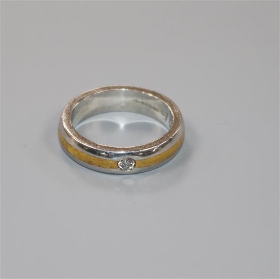 A modern platinum and yellow metal, gypsy set solitaire diamond ring, size L.